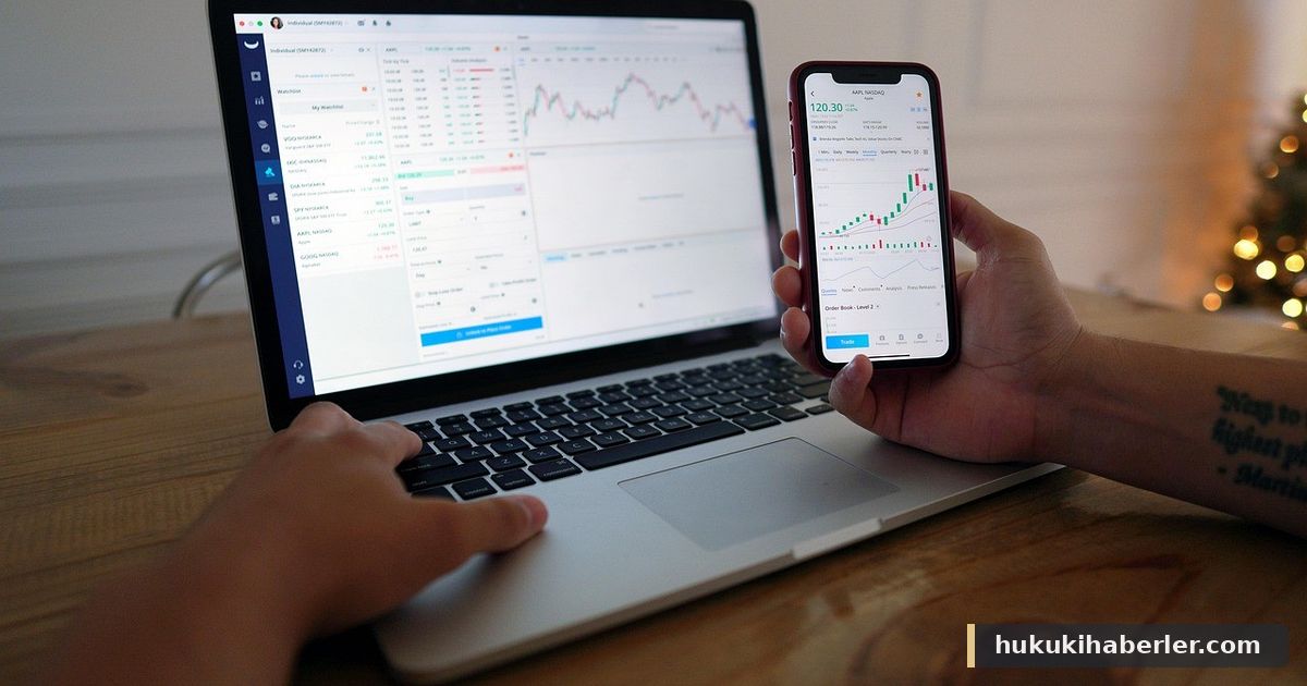 Dizüstü bilgisayar kullanan ve elinde borsa grafikleri olan telefon tutan yatırımcı