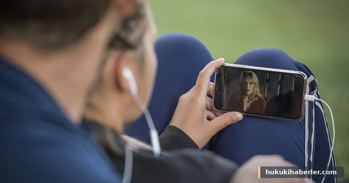 Parkta oturarak akıllı telefondan video izleyen kişilerin arkadan görünümü